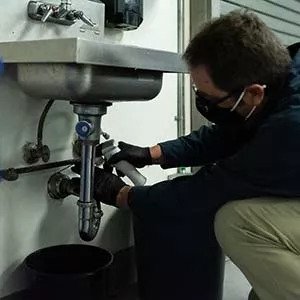 image of worker underneath a sink